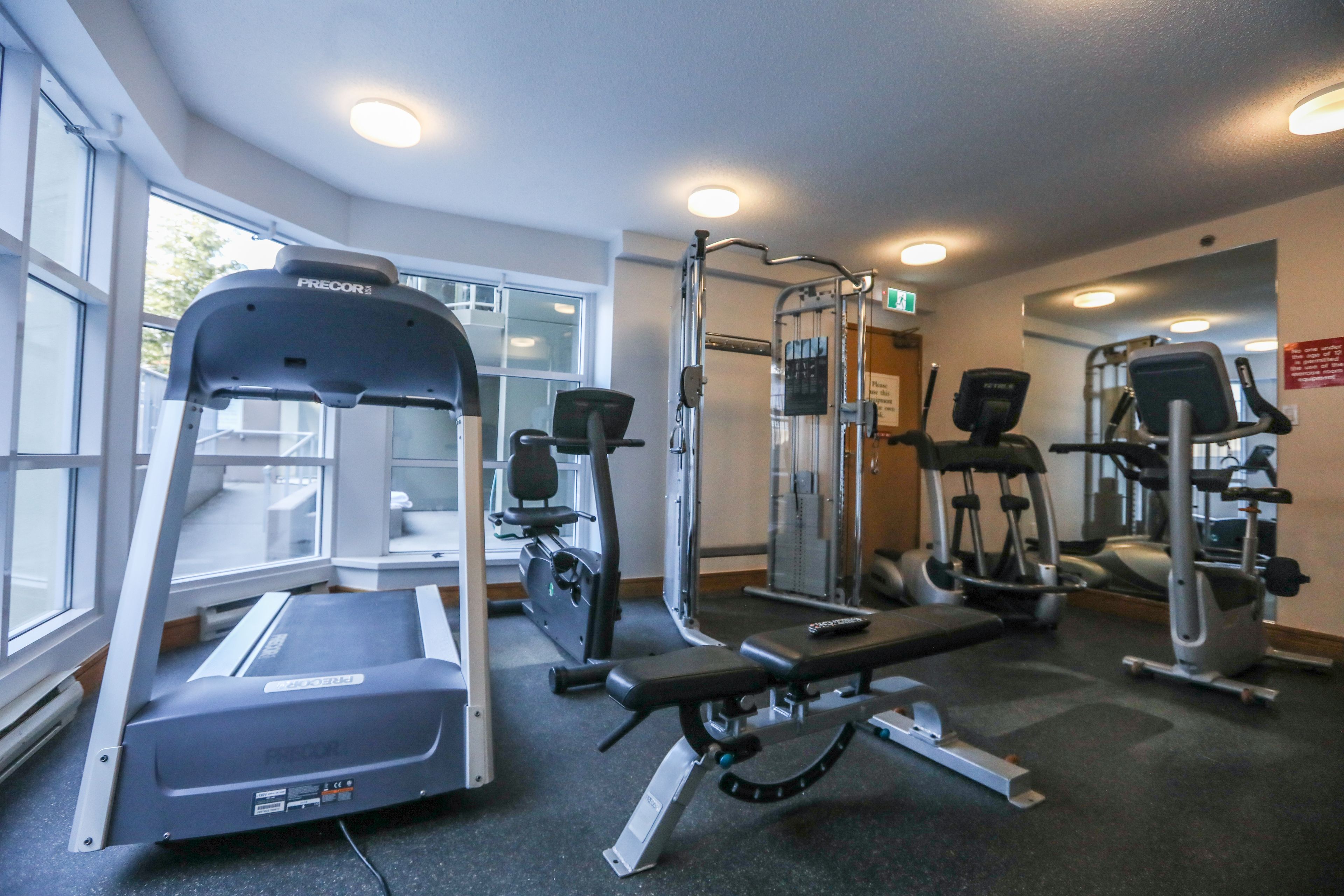 Ein Fitnessraum mit Laufbändern, Kraftgeräten und einer Bank.