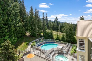 Une piscine dotée d’une plage, entourée d’arbres et bordée d’un bâtiment.