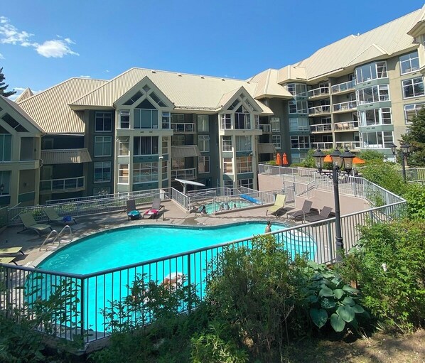 Un hôtel doté d’une piscine entourée de chaises longues et d’une terrasse délimitée par une clôture.
