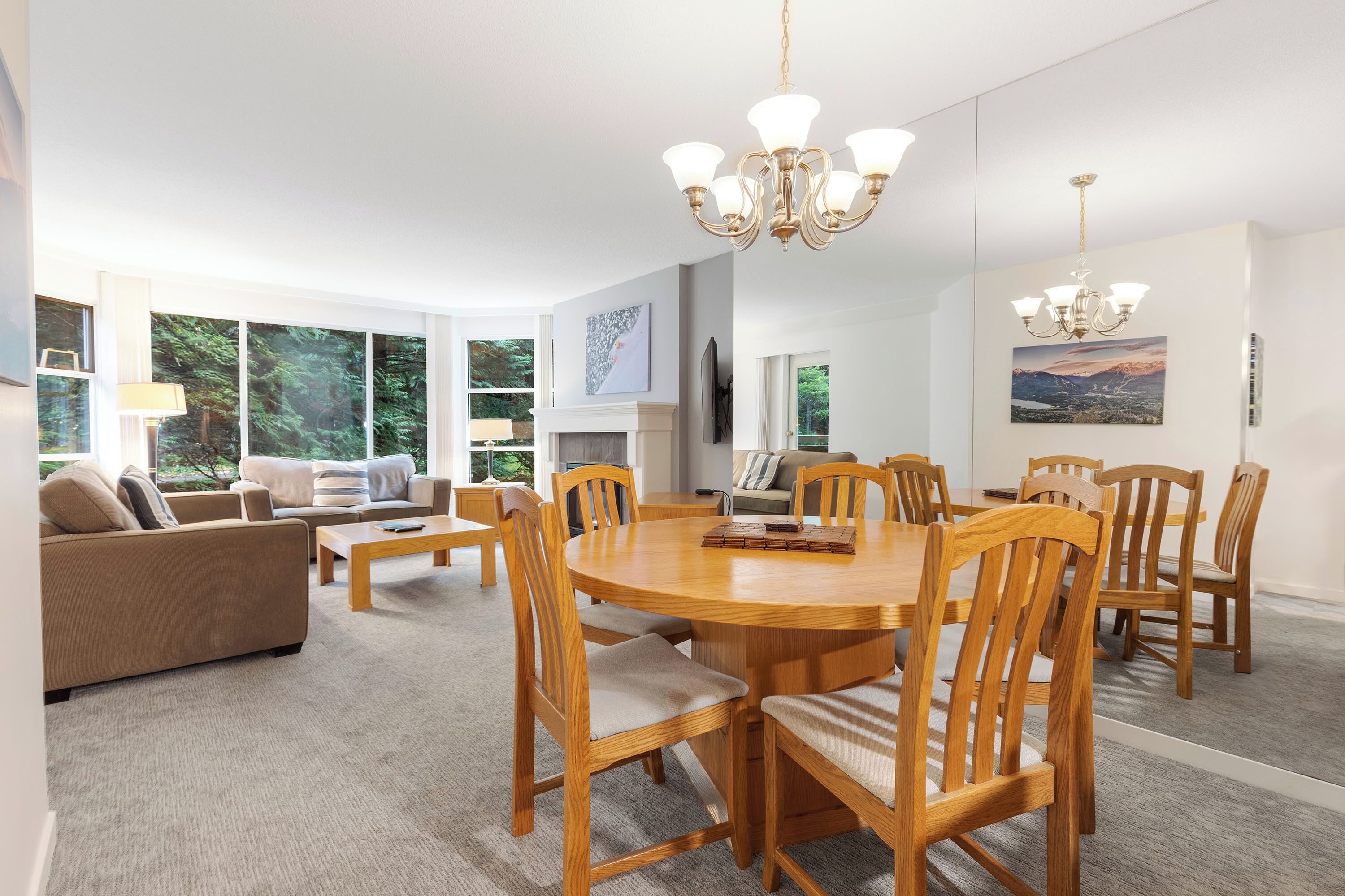 Een ruime woonkamer met een ronde houten eettafel, omringd door stoelen, een bank en een open haard.