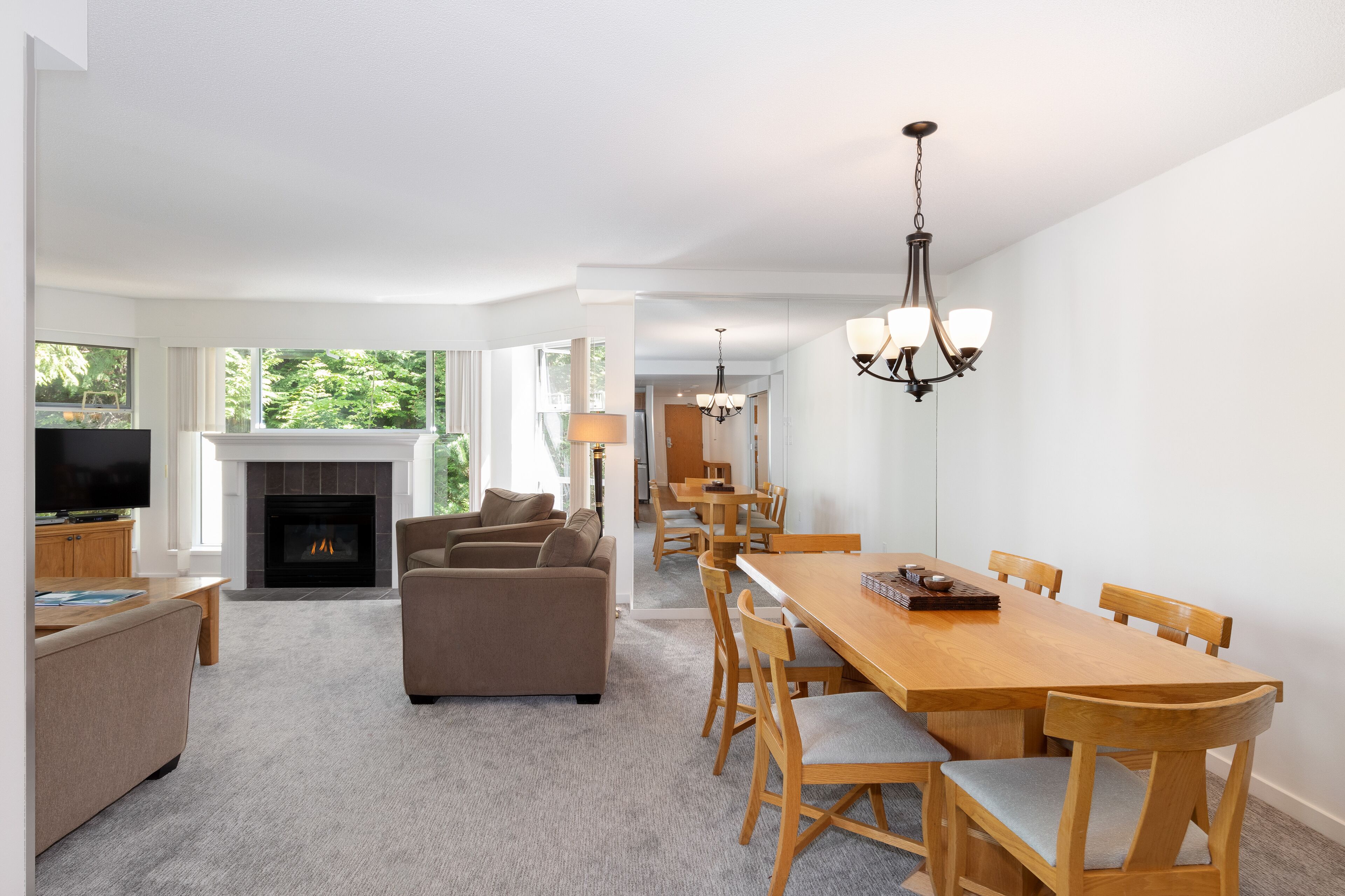 A spacious living room with a fireplace, a dining area with wooden furniture, and a television in the corner.