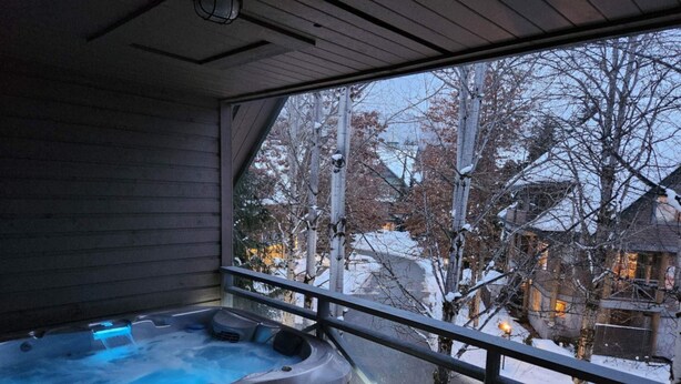 Un jacuzzi en una habitación con un ventanal grande que da a un paisaje nevado.