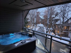 Ett bubbelbad i ett rum med ett stort fönster som vetter ut mot ett snötäckt landskap.