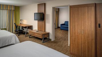 A hotel room with a bed, a desk with a chair, a television, and a wardrobe.
