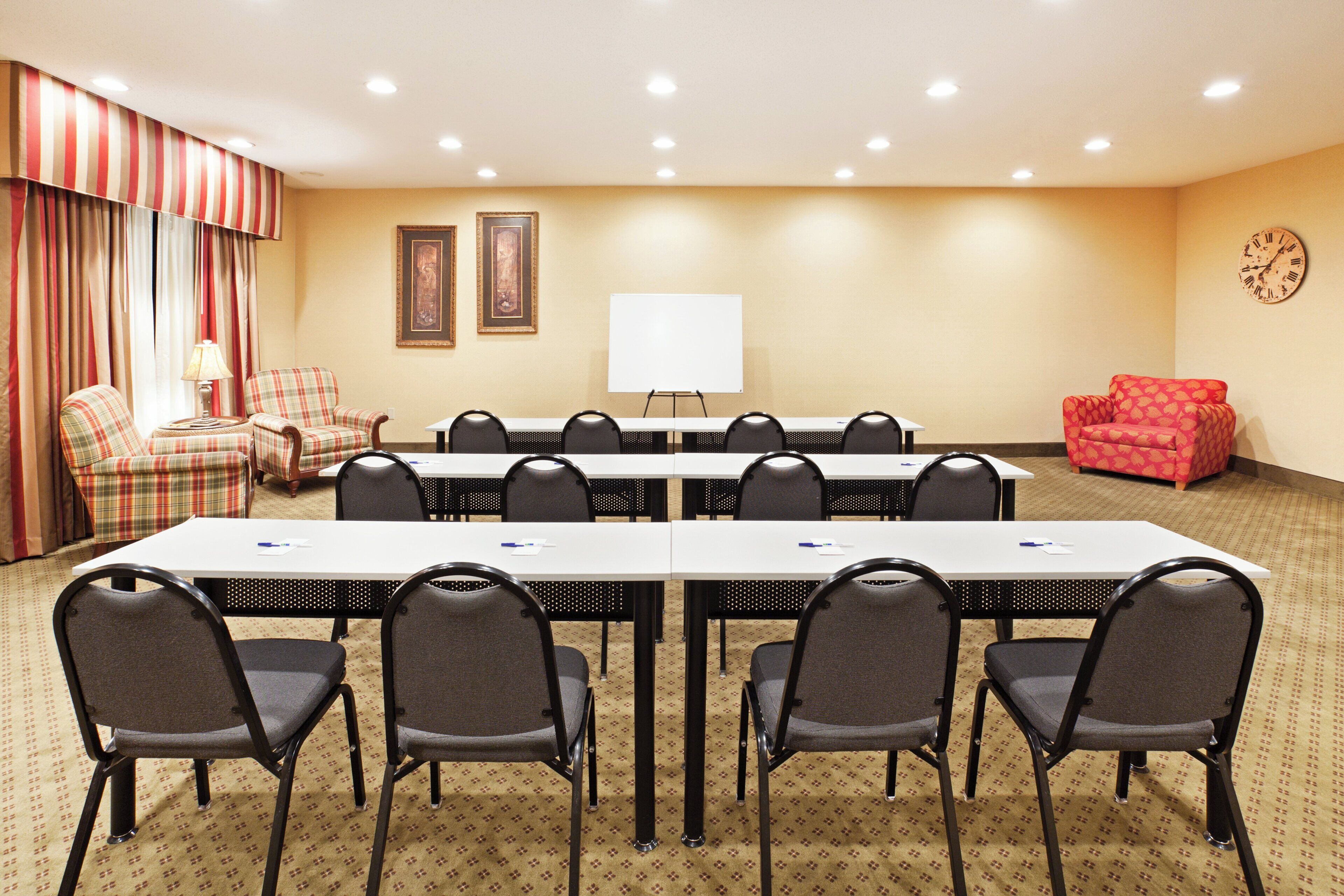 A conference room with a long table, chairs, a whiteboard, and two framed pictures on the wall.
