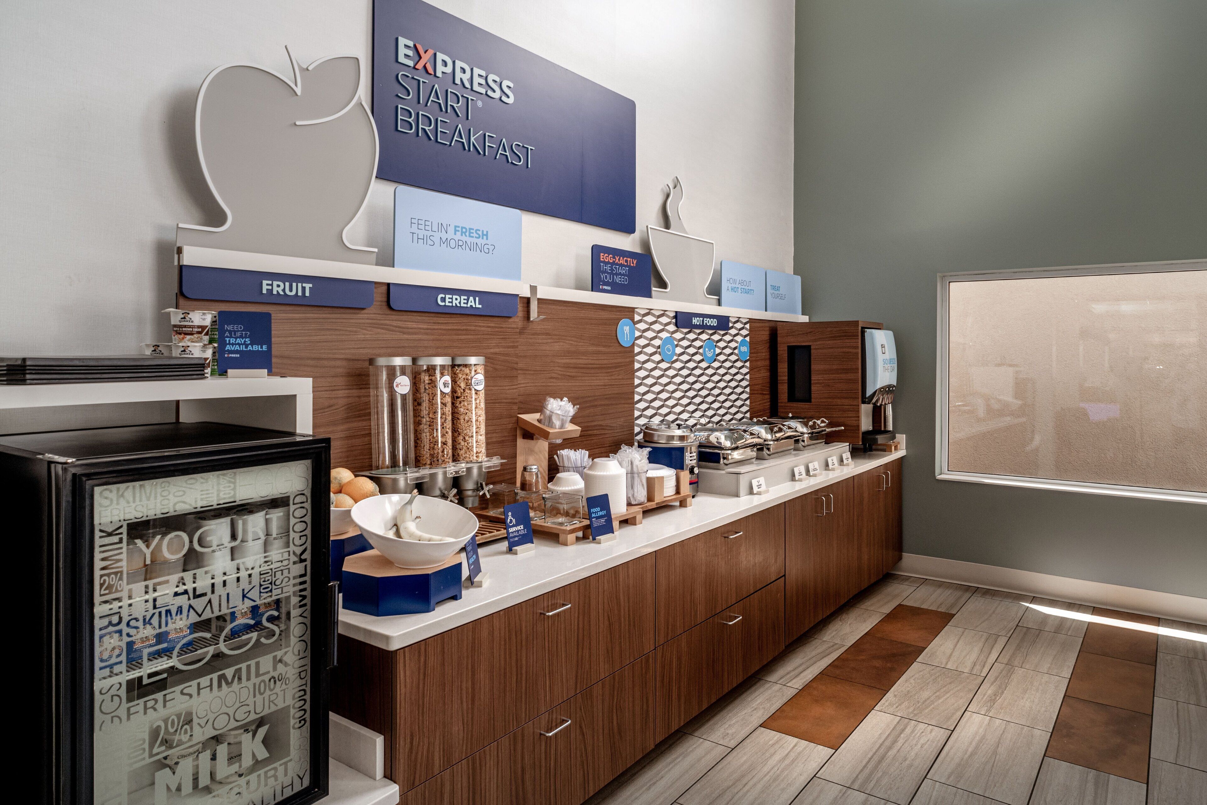 A breakfast bar with a sign reading "EXPRESS START BREAKFAST" and sections labeled "FRUIT" and "CEREAL".