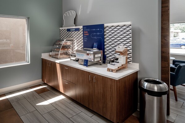 A bakery counter with a sign, a display case, and a trash can.