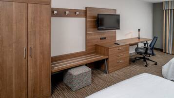 Una habitación de hotel con un escritorio de madera, televisión, cama y una silla.