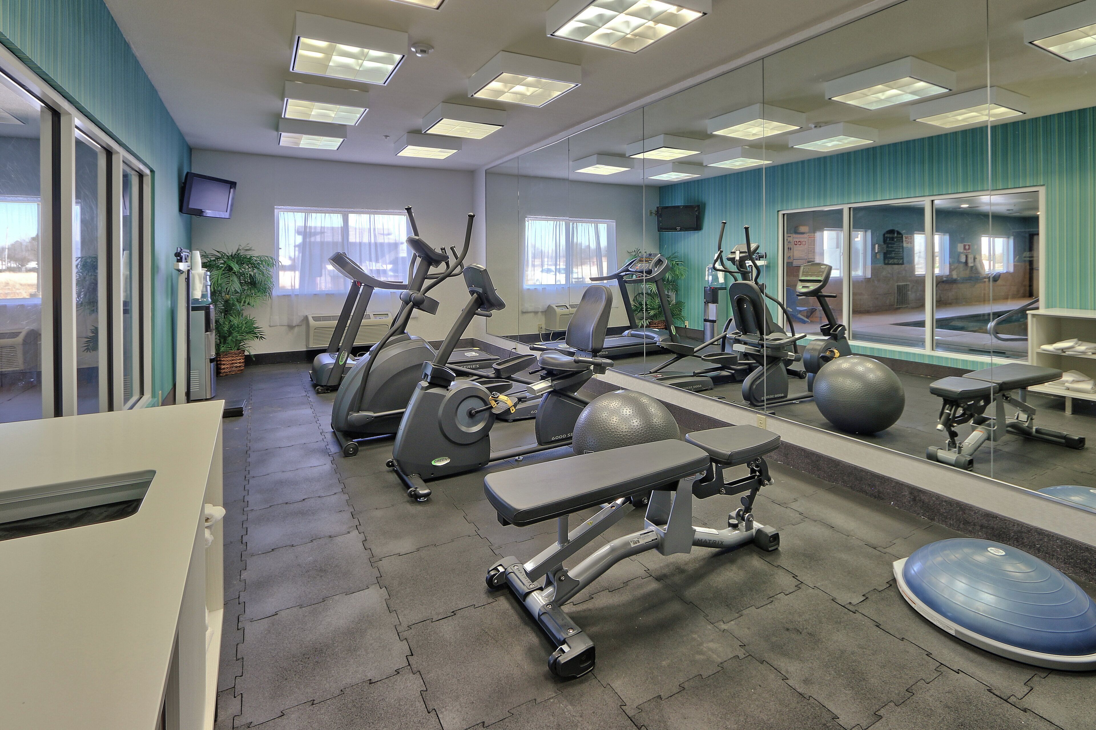 A gym with various exercise equipment, including treadmills, stationary bikes, and weight machines.