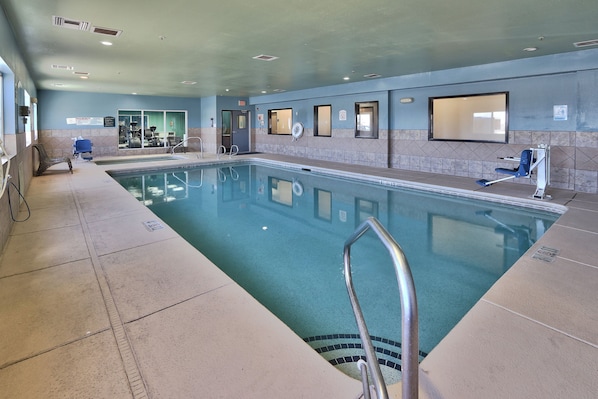 An indoor swimming pool with clear water, a lifeguard chair, and a changing room in the background. - Holiday Express & Suites Portales by IHG (Portales)