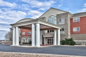 A hotel with a covered entrance, stone facade, and multiple windows. - Holiday Express & Suites Portales by IHG (Portales)