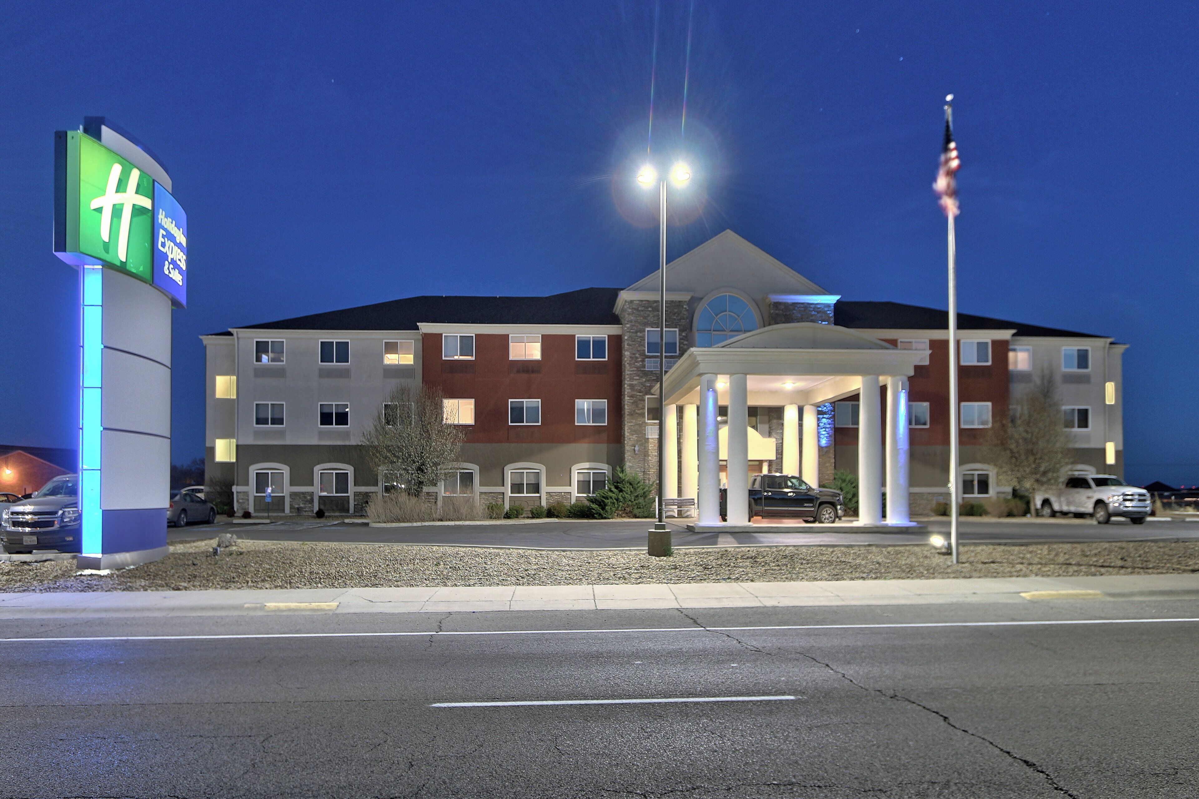 A hotel with a prominent green sign, a covered entrance, and a flagpole.