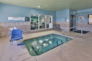 A pool area with a blue chair, exercise equipment, and a sign indicating emergency procedures.