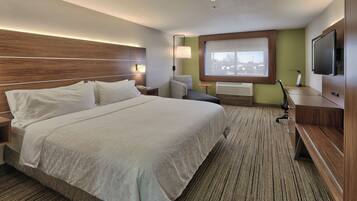 Habitación de hotel con una cama grande, un escritorio, una silla, un televisor y una ventana con vistas.