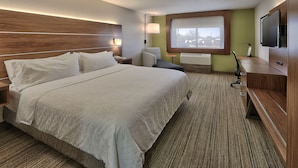 A hotel room with a large bed, a desk, a television, and a window with a view. - Holiday Express & Suites Portales by IHG (Portales)