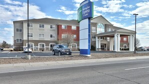 A Holiday Inn Express & Suites with a large sign, a parking lot, and a building with a mix of red and beige exterior. - Holiday Express & Suites Portales by IHG (Portales)