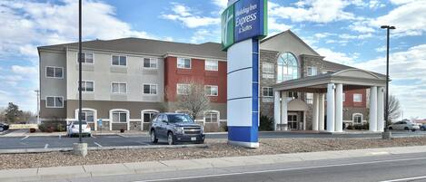 A Holiday Inn Express & Suites with a large sign, a parking lot, and a building with a mix of red and beige exterior.