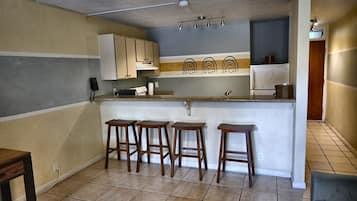 Eine Küche mit vier Holzhockern, einer Arbeitsplatte, Schränken und einer Deckenleuchte.