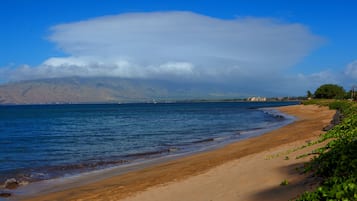 På stranden, hvidt sand, parasoller, badehåndklæder