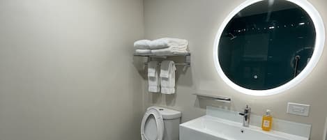 Une salle de bain moderne avec des toilettes, un lavabo et un miroir rond.
