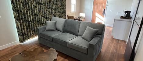 En moderne stue med en grå sofa, et træbord og en loftventilator.