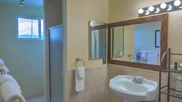 A bathroom with a sink, mirror, and shower.