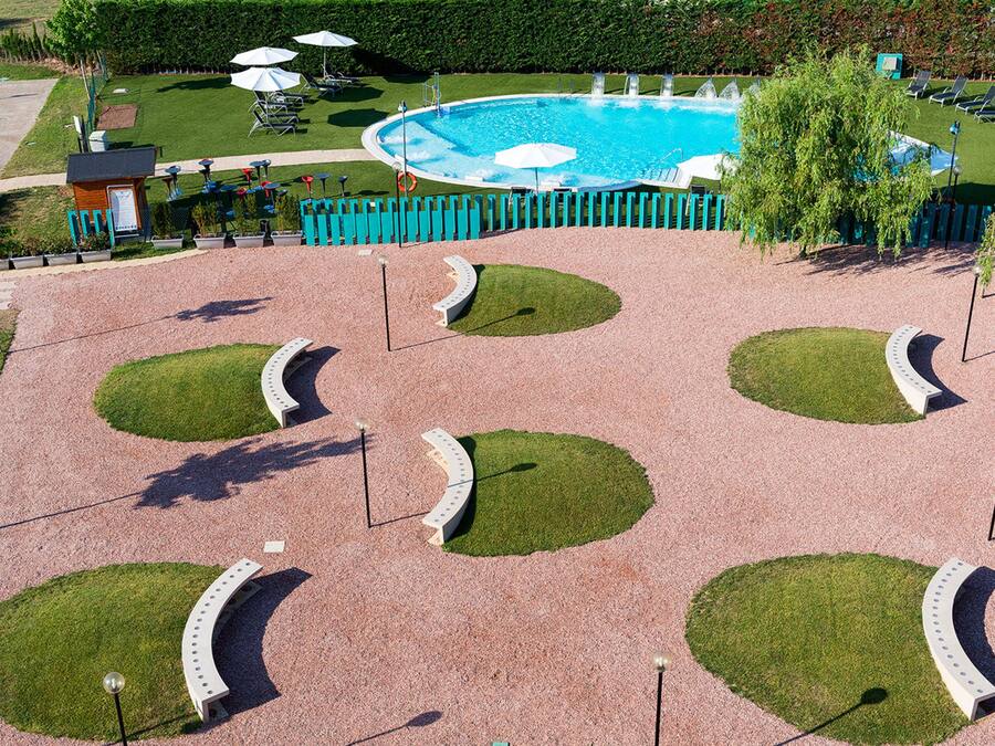 Zona ajardinada con piscina, tumbonas y un pequeño edificio.
