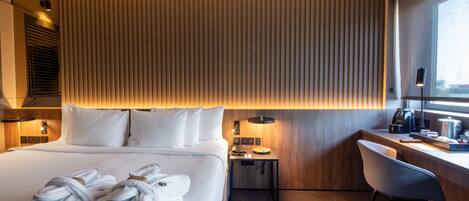 Une chambre d’hôtel moderne avec un grand lit, une table de chevet et un bureau avec une chaise.