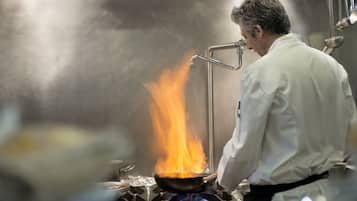 A chef cooking with a pan on a stove with flames.