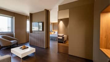 A modern hotel room with a sofa, a coffee table, a TV, and a bed.