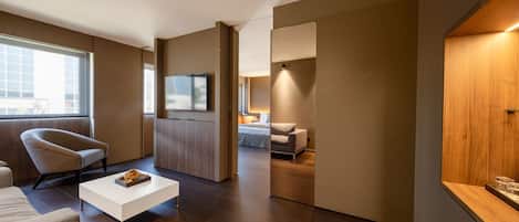 Una habitación de hotel moderna con un sofá, una mesa de centro, un televisor y una cama.