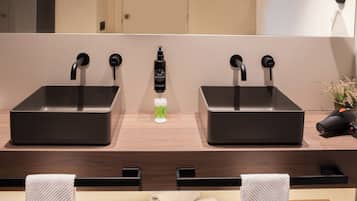 Un baño moderno con dos lavamanos, un espejo y un secador de pelo en la encimera.