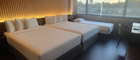 A modern bedroom with a large bed, a bedside table, a chair, and a window with a view of trees.