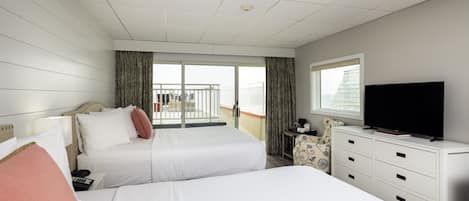 Habitación de hotel con dos camas, televisión, escritorio y balcón con cortinas.