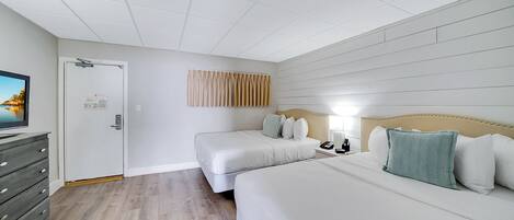 Una habitación de hotel con dos camas, un aparador, un televisor y una puerta con un cartel.