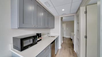 A modern kitchen with grey cabinets, a microwave, and a coffee maker.