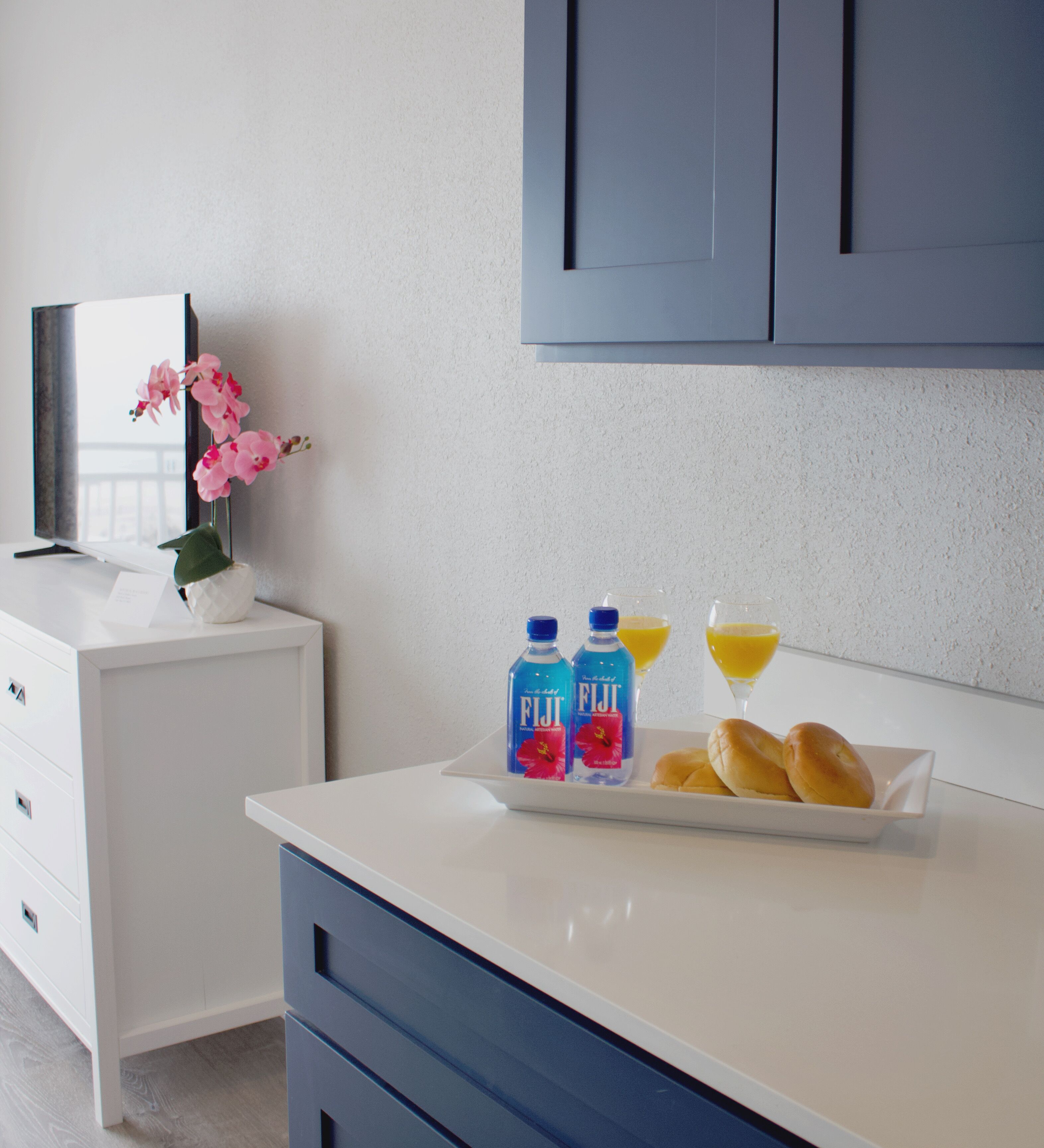 A kitchen with a white countertop, a blue cabinet, and a white drawer unit.