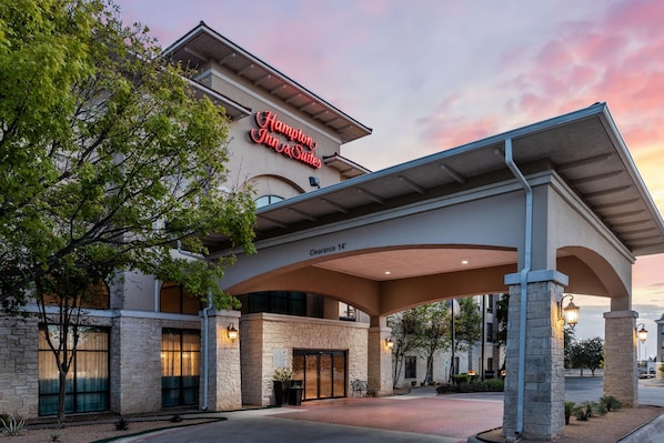 A Hampton Inn & Suites with a covered entrance, stone facade, and a sign indicating a clearance of 14 feet.