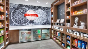 A snack and sundries section with a 'TREAT' sign, shelves stocked with snacks, and refrigerated drinks. - Hampton Inn & Suites Rockport-Fulton (Fulton)