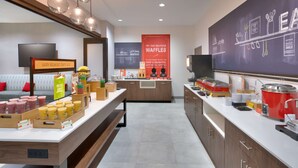 A breakfast area with a waffle station, juice dispensers, and a chalkboard menu. - Hampton Inn & Suites Rockport-Fulton (Fulton)