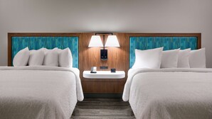 A hotel room with two beds, a bedside table with a phone and a digital clock, and a wall-mounted lamp. - Hampton Inn & Suites Rockport-Fulton (Fulton)