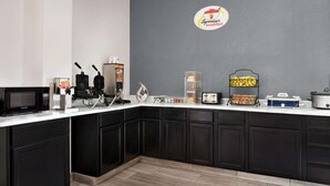 A modern kitchen with dark cabinetry, a microwave, a waffle maker, and a coffee machine.