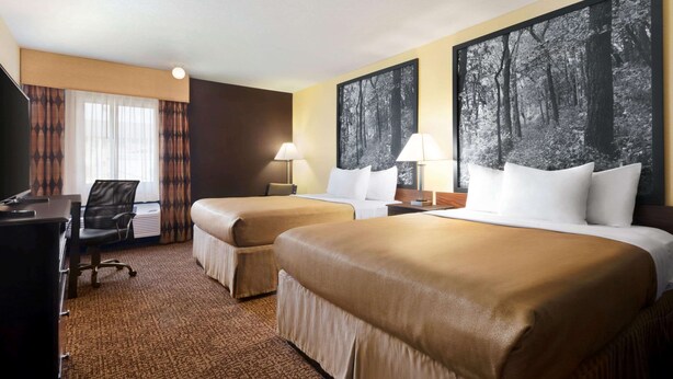 A hotel room with two beds, a desk, and a chair.