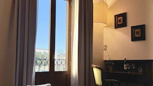 A hotel room with a bed, a desk, a chair, a lamp, and a window with curtains. - Hotel Relais Il Cestello (Florence)