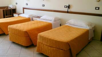 A hotel room with three single beds, a desk, and a chair.