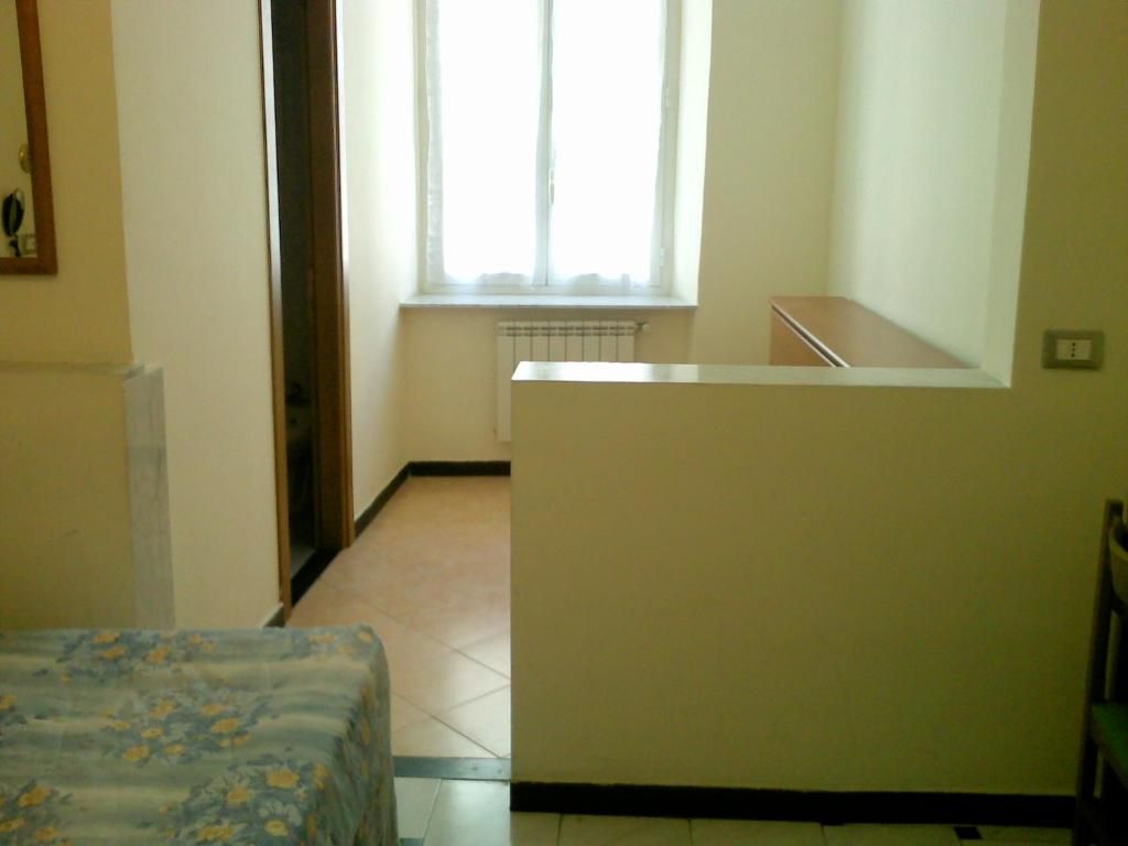 Una habitación con cama, un radiador, una ventana con cortinas y una escalera.
