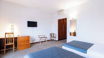 A hotel room with a bed, a desk with a chair, a TV, and a wardrobe.