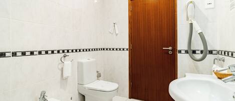 A modern bathroom with a toilet, bidet, sink, and bathtub.