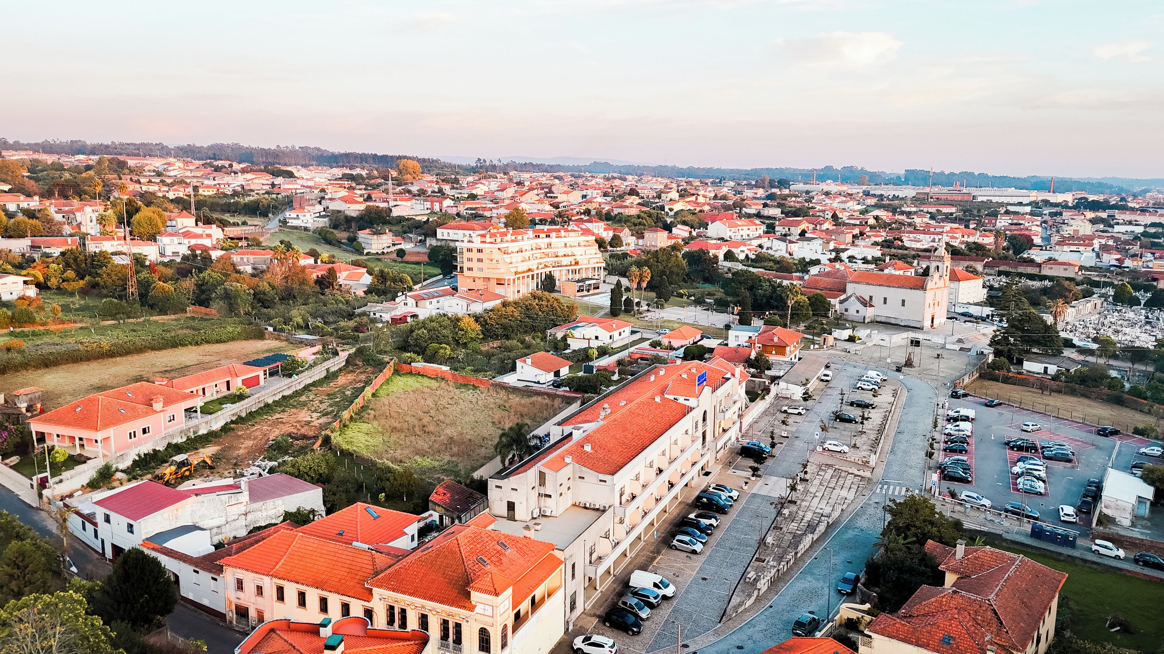 An aerial view of a town with red-roofed buildings, a central street, and a large church.