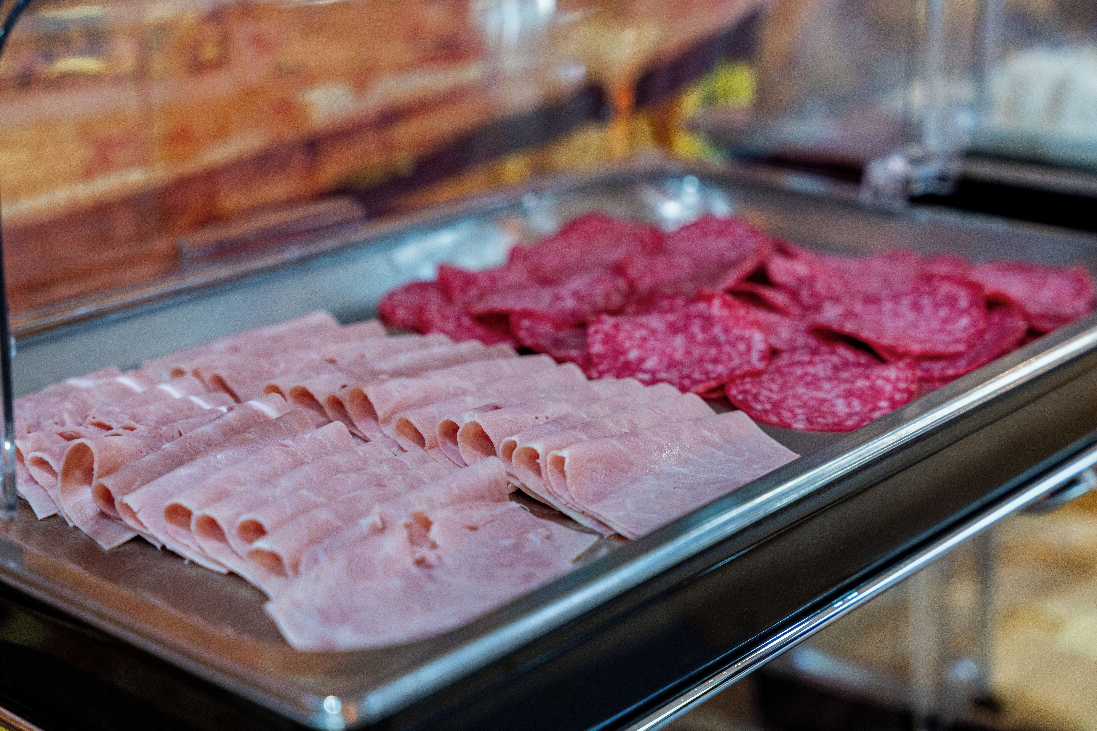 A display case with sliced meats, including ham and salami.